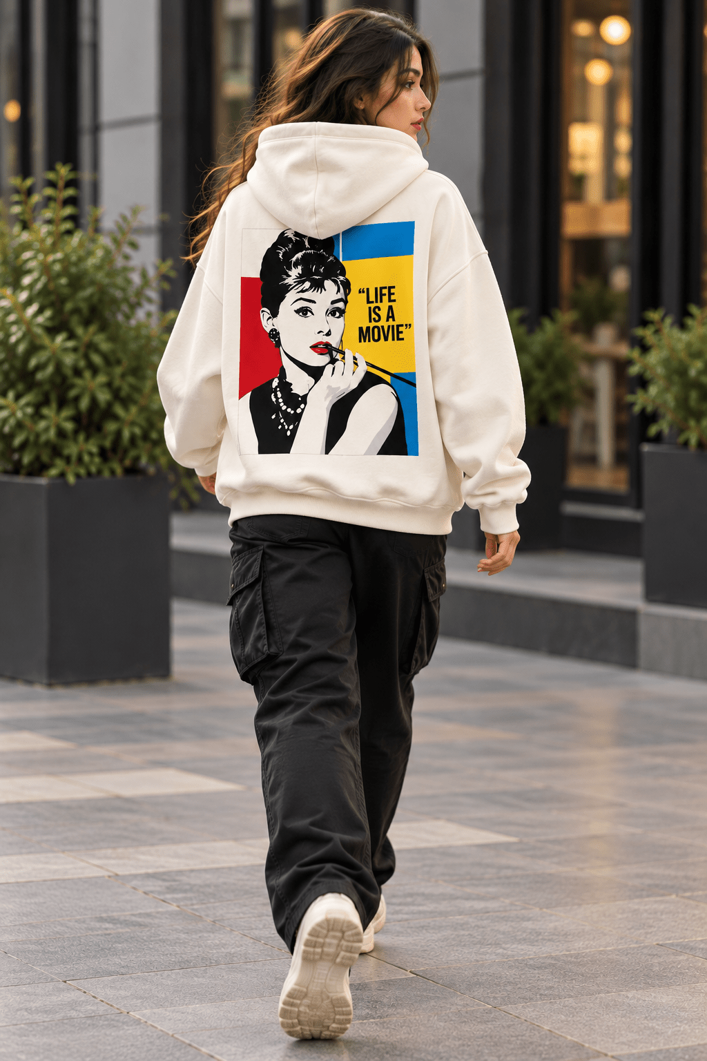 Female model wearing TEEZO Life Is A Movie graphic hoodie from back