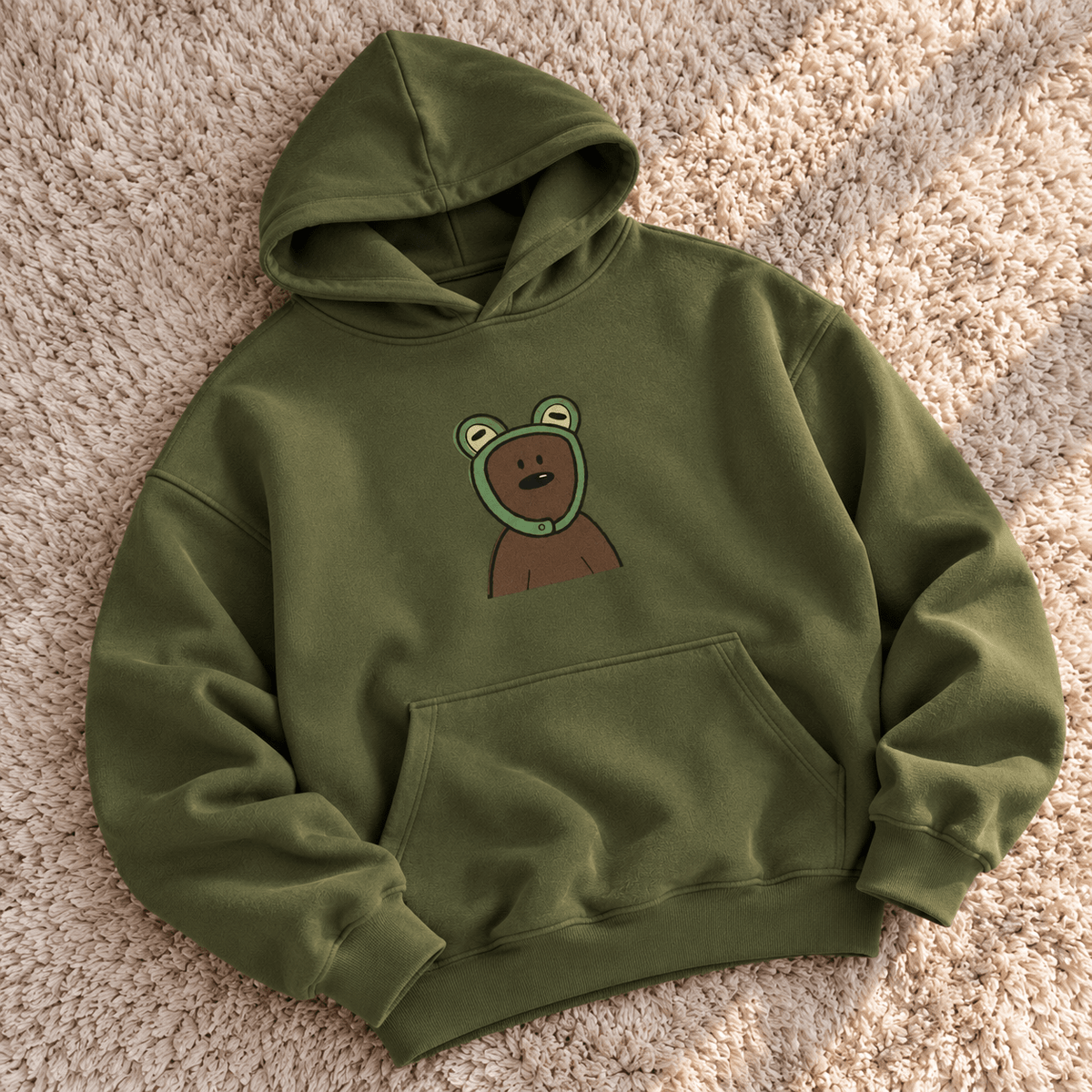 TEEZO olive green oversized hoodie with a cute cartoon bear graphic on the front, styled on a female model in a casual indoor setting.