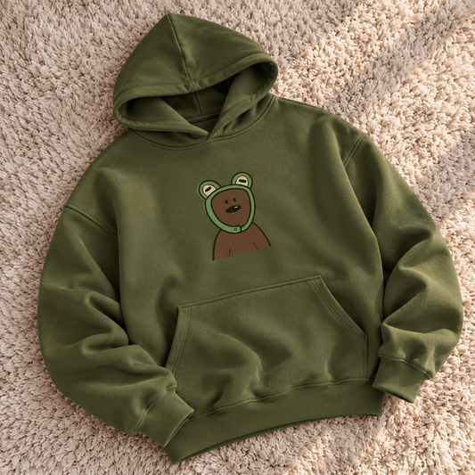 TEEZO olive green oversized hoodie with a cute cartoon bear graphic on the front, styled on a female model in a casual indoor setting.